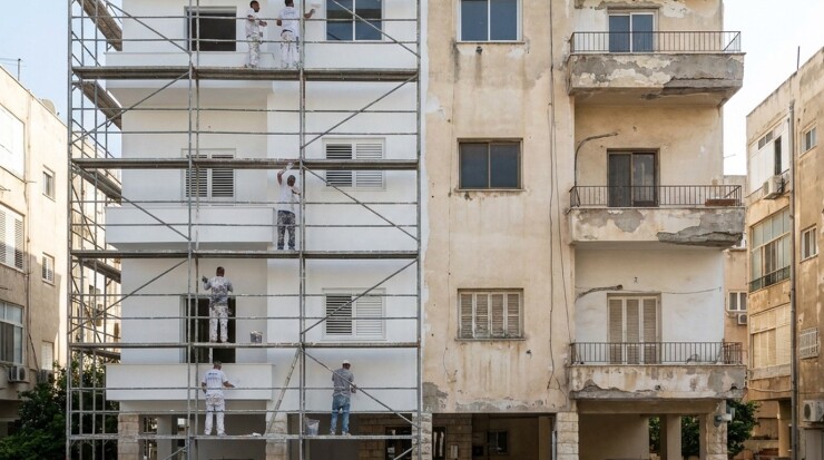 צביעה חיצונית בפיגומים בבניין משותף, מחצית מהחזית כבר מחודשת