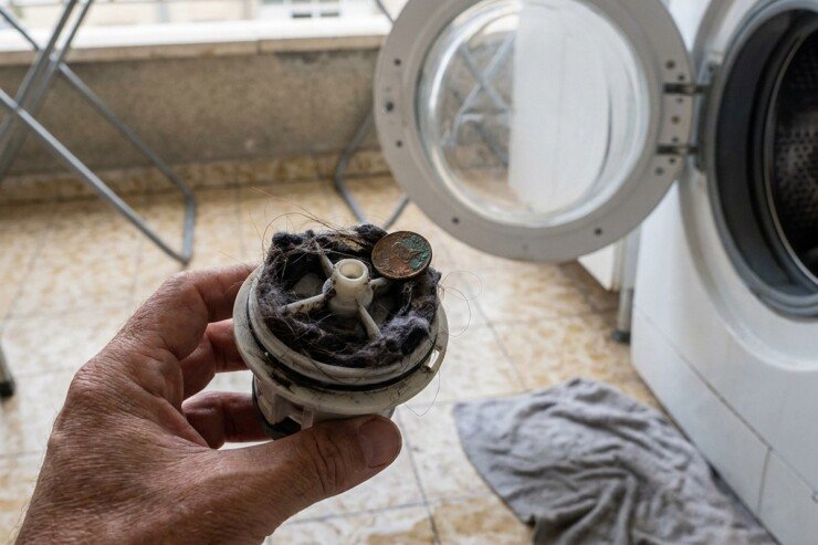 פילטר של מכונת כביסה שהוצא מהמכונה, ובתוכו מטבע וסיבים שהצטברו