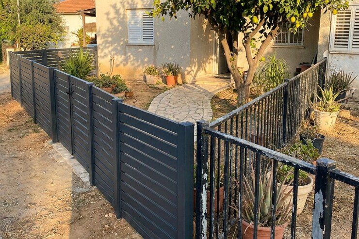 גדר אלומיניום לצד גדר סורגים מברזל בחצר בית פרטי