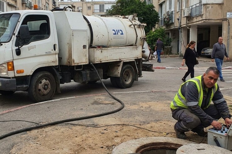 ביובית פותחת סתימה בשוחת ביוב בחצר בניין